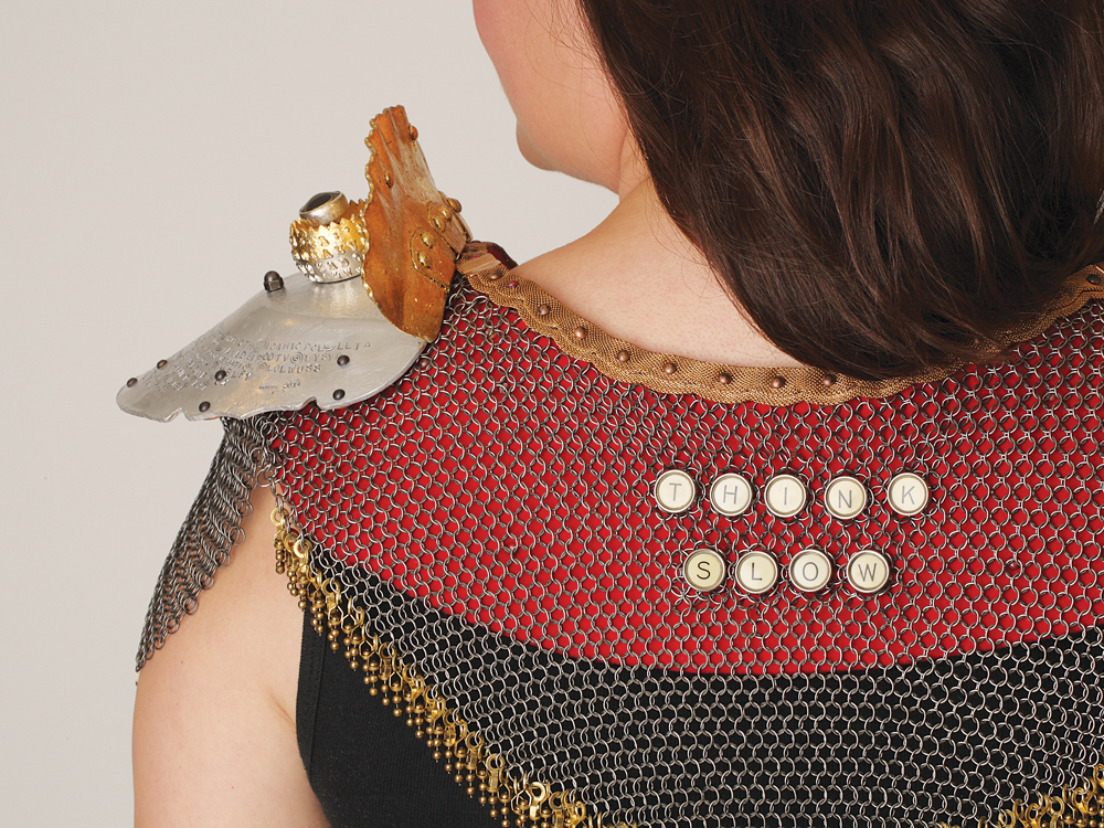 Ornate chainmail mantle with lettering and metal shoulder plate draped over a persons shoulders