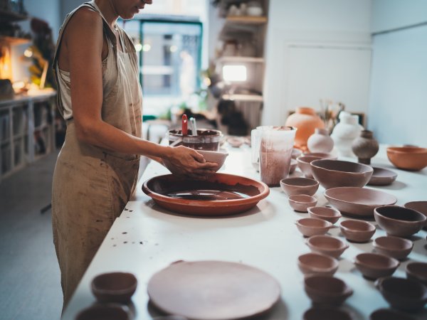 ceramic artist work at table with various unfired dishes