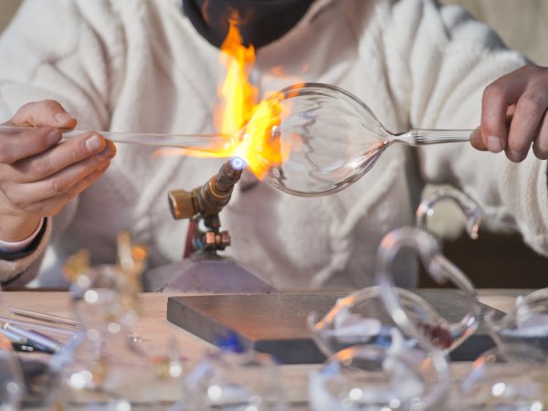 artist manipulating glass bulb with flame