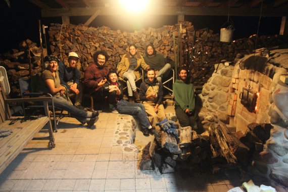 group of people posing for a photo beside a wood fired kiln at night time