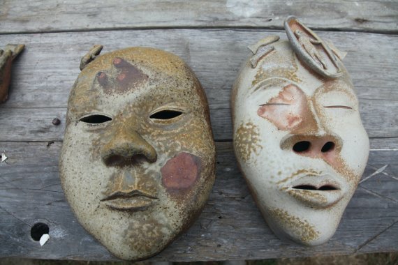 a pair of wood fired ceramic masks