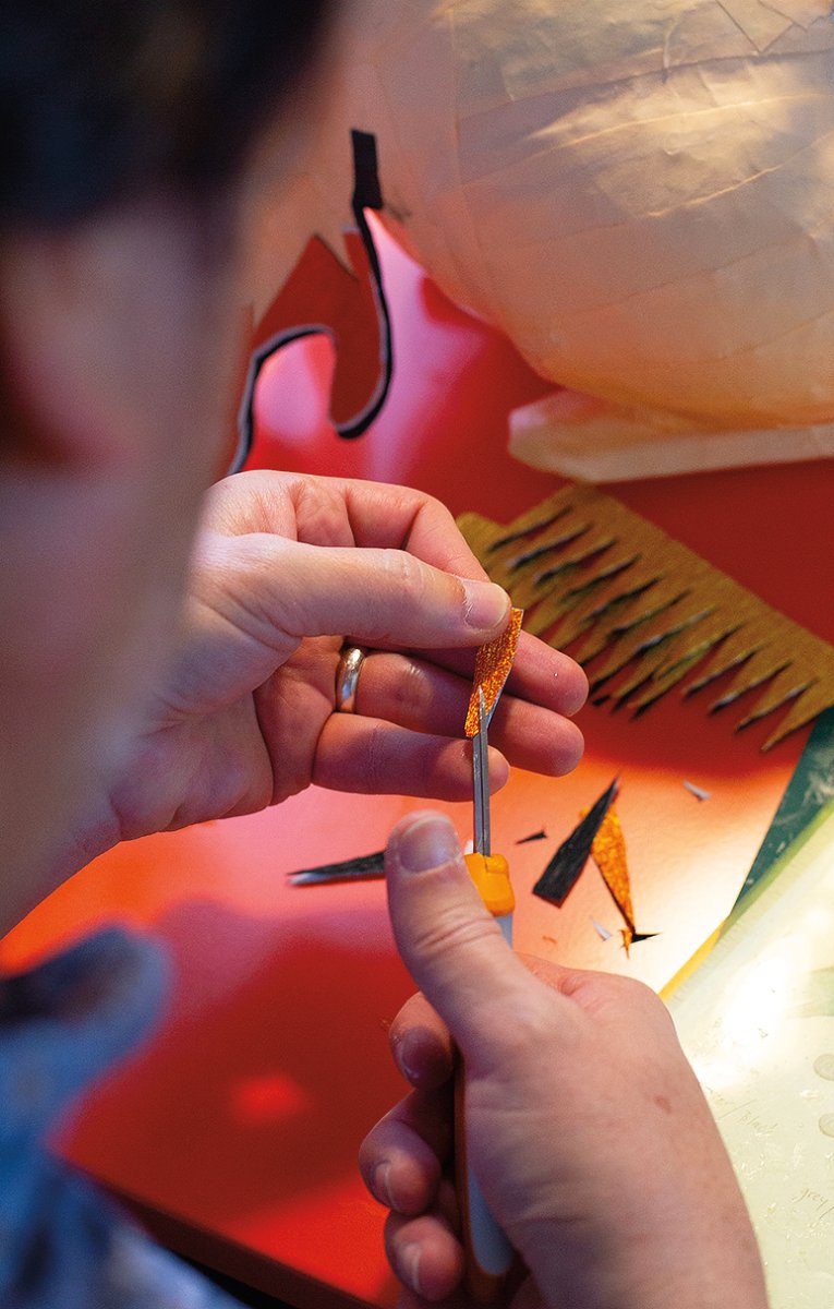 The artist cuts minute details into a multilayered piece of crepe paper fringe, which creates a desired pattern when applied with glue to a piñata sculpture. Photos by James Bernal.