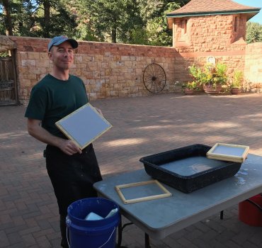 Drew demonstrates paper making in a sunny courtyard
