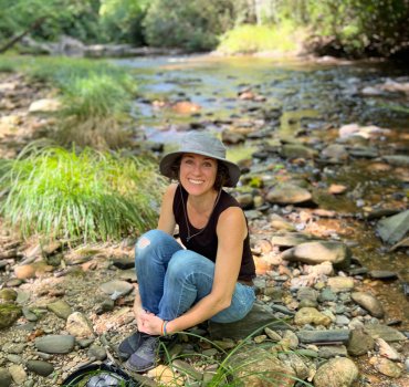 portrait of jeannine marchand with camera beside creek