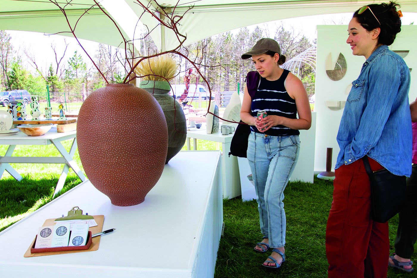 Customer looking at pottery work on the lawn of Ani Kasten's home studio.