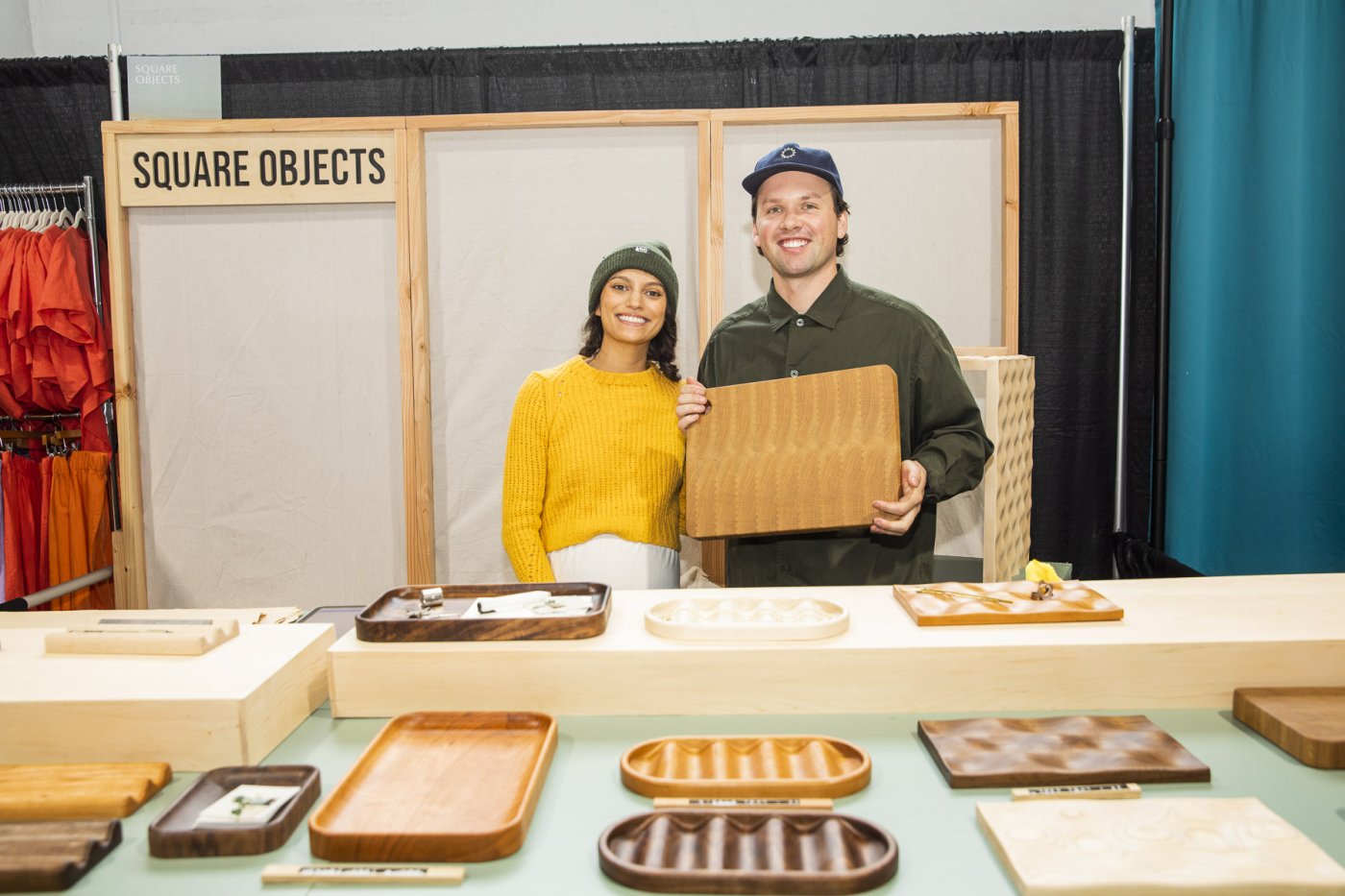Two artists pose with their wavy woodwork trays and cutting boards.