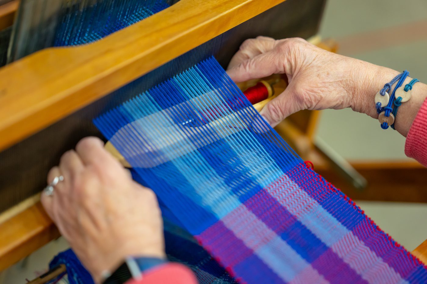 Textile artist weaves on a loom. Photo by Max Franz.