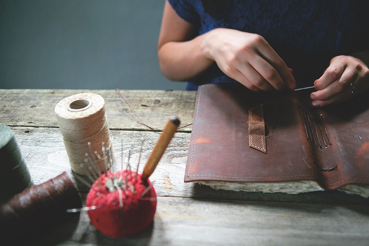 Winn hand-binds a leather journal using the long-stitch method. Photo by Kelley Schuyler.