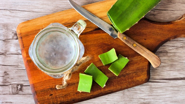 Aloe vera with a knife and jar of gel on a cutting board