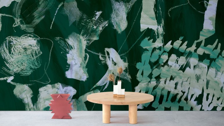 Small wooden table with center piece beside wall with bold green textured wallpaper