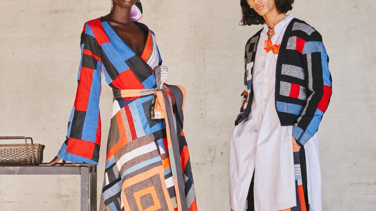 two models wearing garments made from colorful patchwork quilt with orange black red and earth tones