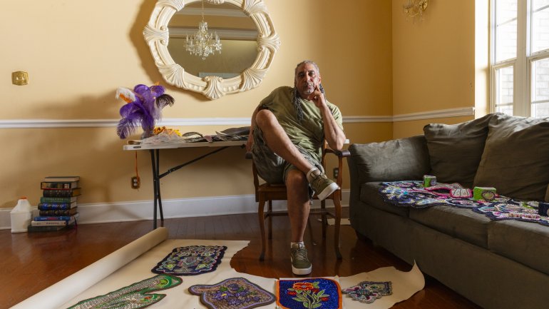 Charles DuVernay, a Black Masking Indian, in his home with a spread of his beaded works. Photo by Cedric Angeles.