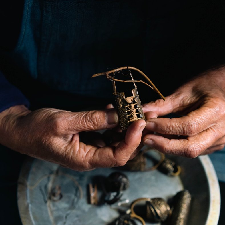 Suzye Ogawa uses intricate processes to make miniature vessels from bronze and natural materials. Here, she inspects and finishes several pieces. Photo by Nik Z Photo.