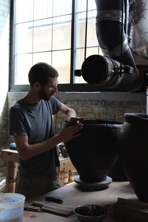 Person working on a large ceramic vessel in historic studio space