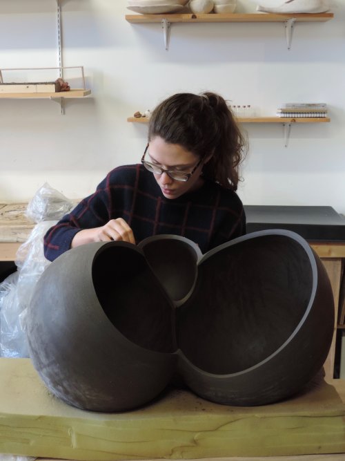 Person working on a large ceramic vessel in a studio space
