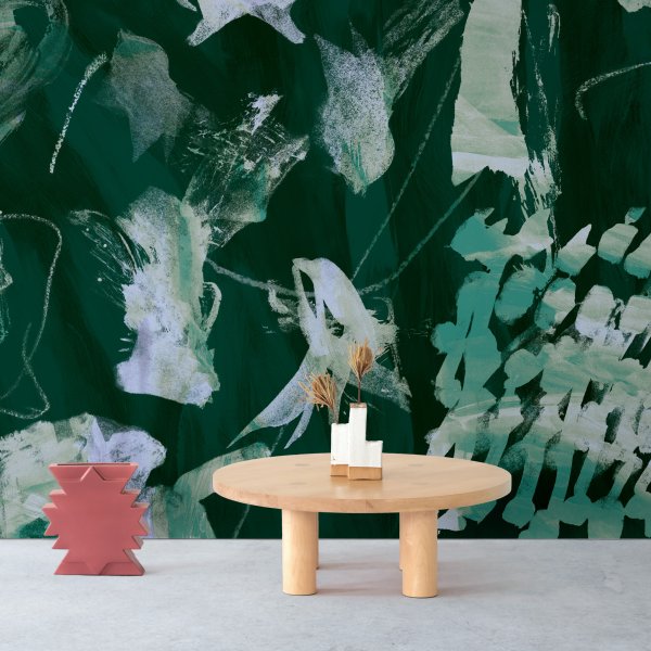 Small wooden table with center piece beside wall with bold green textured wallpaper
