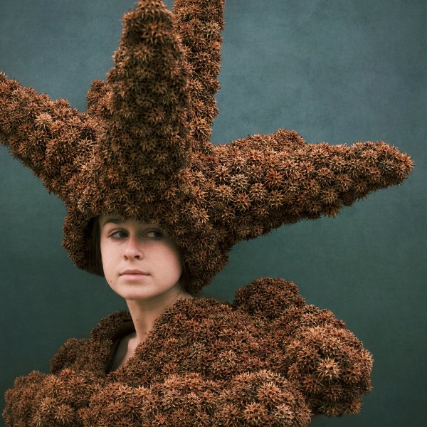 model wearing sculptural headpiece and top made from spiky fruit pods from a tree