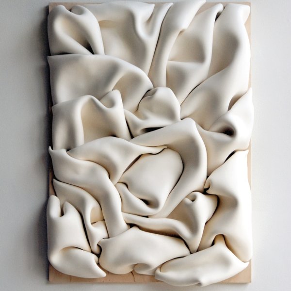 white clay folded into itself on plywood