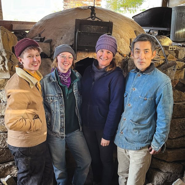 group of four standing in front of kiln smiling