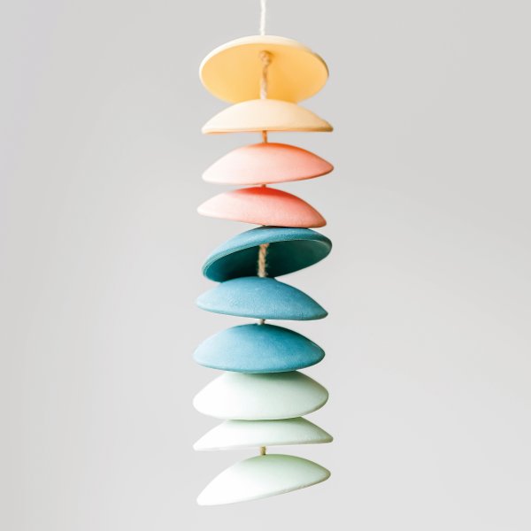 Multiple colors of stoneware clay stacked on top of each other making a wind chime.