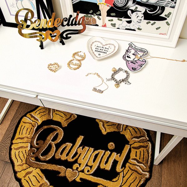 On a table in Romero’s home office: her gold nameplate, custom bamboo gold hoops, and custom bamboo ring—all with the name “LaLa.” Her company Bella Doña makes the “Babygirl” bamboo hoop rug on the floor.