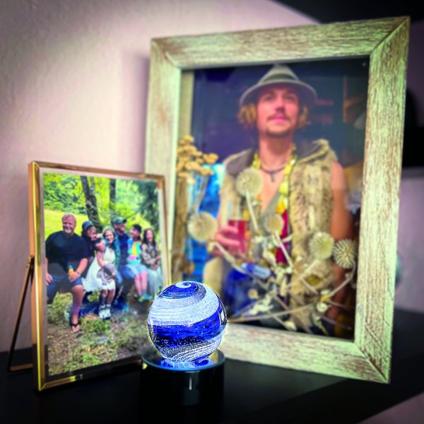 Memorial featuring 2 images of a man and his family plus a piece of blown glass.