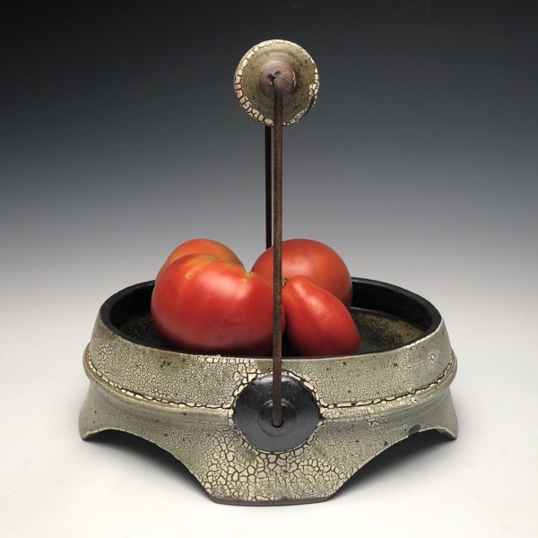 Handcrafted ceramic and metal tray holding tomatoes.