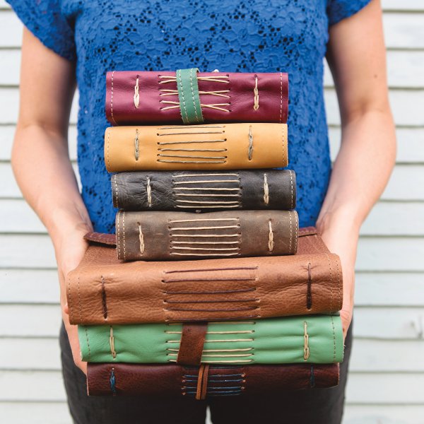 Megan Winn holds a stack of her handbound journals, created using reclaimed leather, handmade cotton rag paper, and antique findings. Photo by Kelley Schuyler.