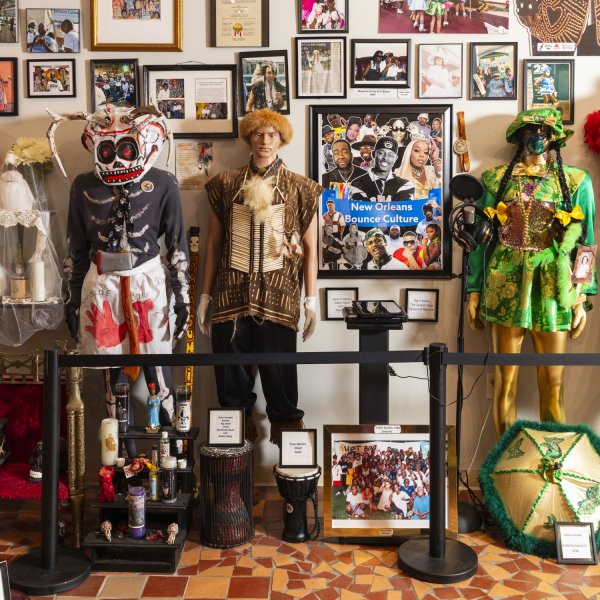 Framed photos cover the walls, multiple mannequins are dressed in elaborate masks and clothing in celebration of New Orleans. 
