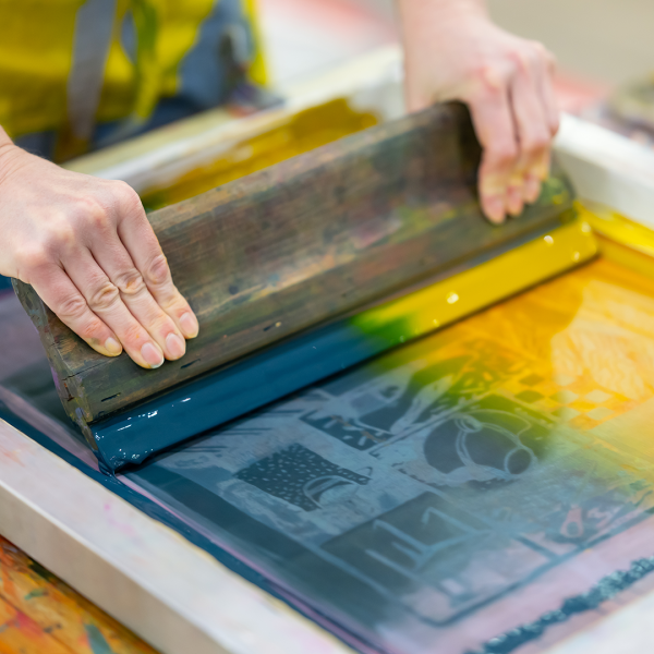 Artist screen printing a canvas tote bag.