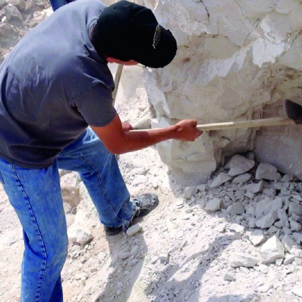 A man uses a tool to gather pumice stone.
