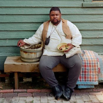 Michael Twitty in historic garb holding a bowl of food