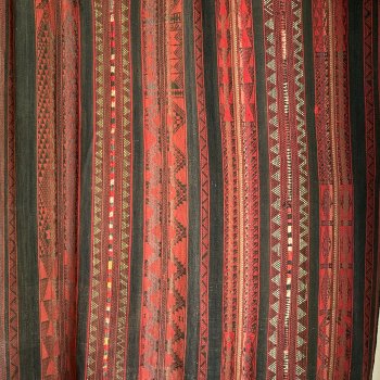 handwoven carpet with striped patterns that are predominantly red with some black