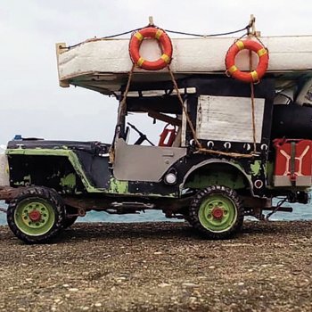 model of a jeep with a barge made from a mattress tied to the top and various gear tied to the back pictured on a shoreline