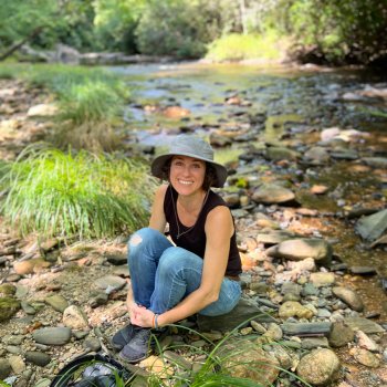 portrait of jeannine marchand with camera beside creek