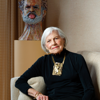 Dorothy Saxe sitting with some of her craft collection. BUST: Robert Arneson, A Hollow Jesture, 1971, glazed ceramic, 20.25 x 12.5 x 14 in.  NECKLACE: Pal and Lumi Kepenyes, untitled necklace, ca. 1985, brass, 11 x 4.5 x 1 in. Photo courtesy of Craig Lee/The Examiner.
