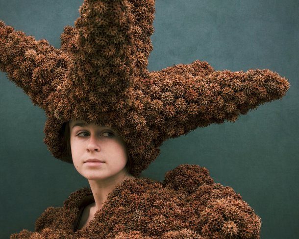 model wearing sculptural headpiece and top made from spiky fruit pods from a tree