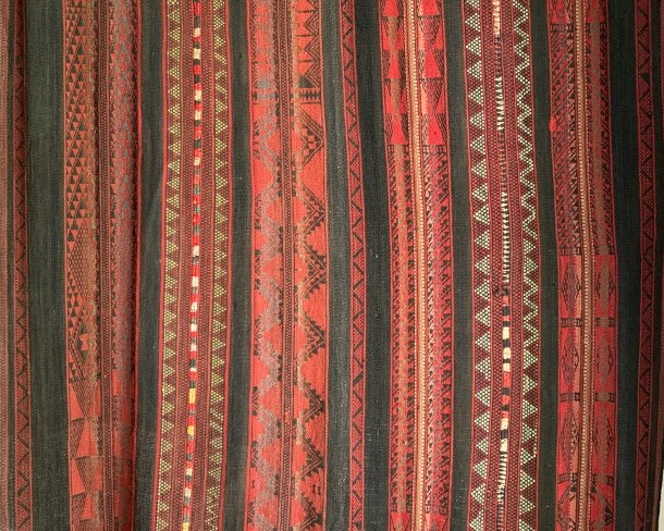handwoven carpet with striped patterns that are predominantly red with some black