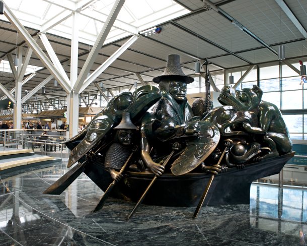 bronze sculpture shown in an airport terminal depicting figures and animals in a boat with oars