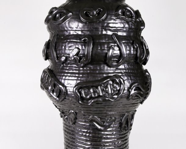 shiny black ceramic vessel with coiled texture and various shapes on the surface