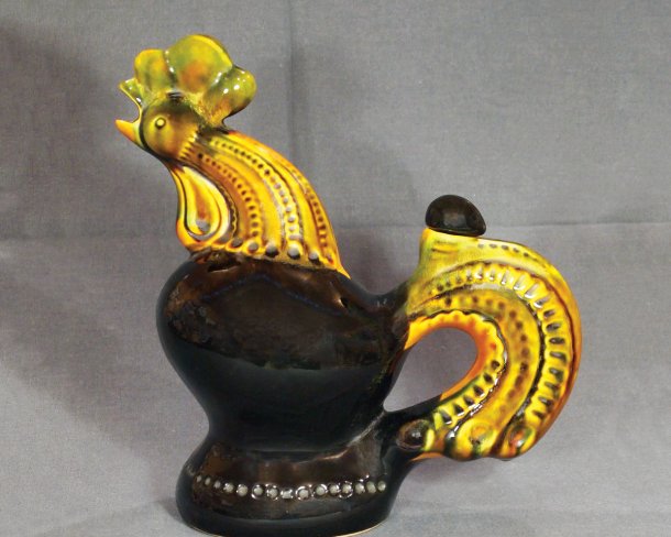 ceramic jug in the shape of a rooster with yellow head and tail and black body