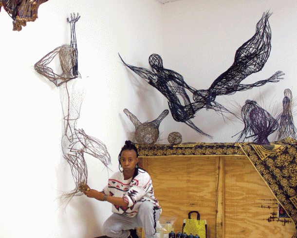 woman crouching in studio working on art piece